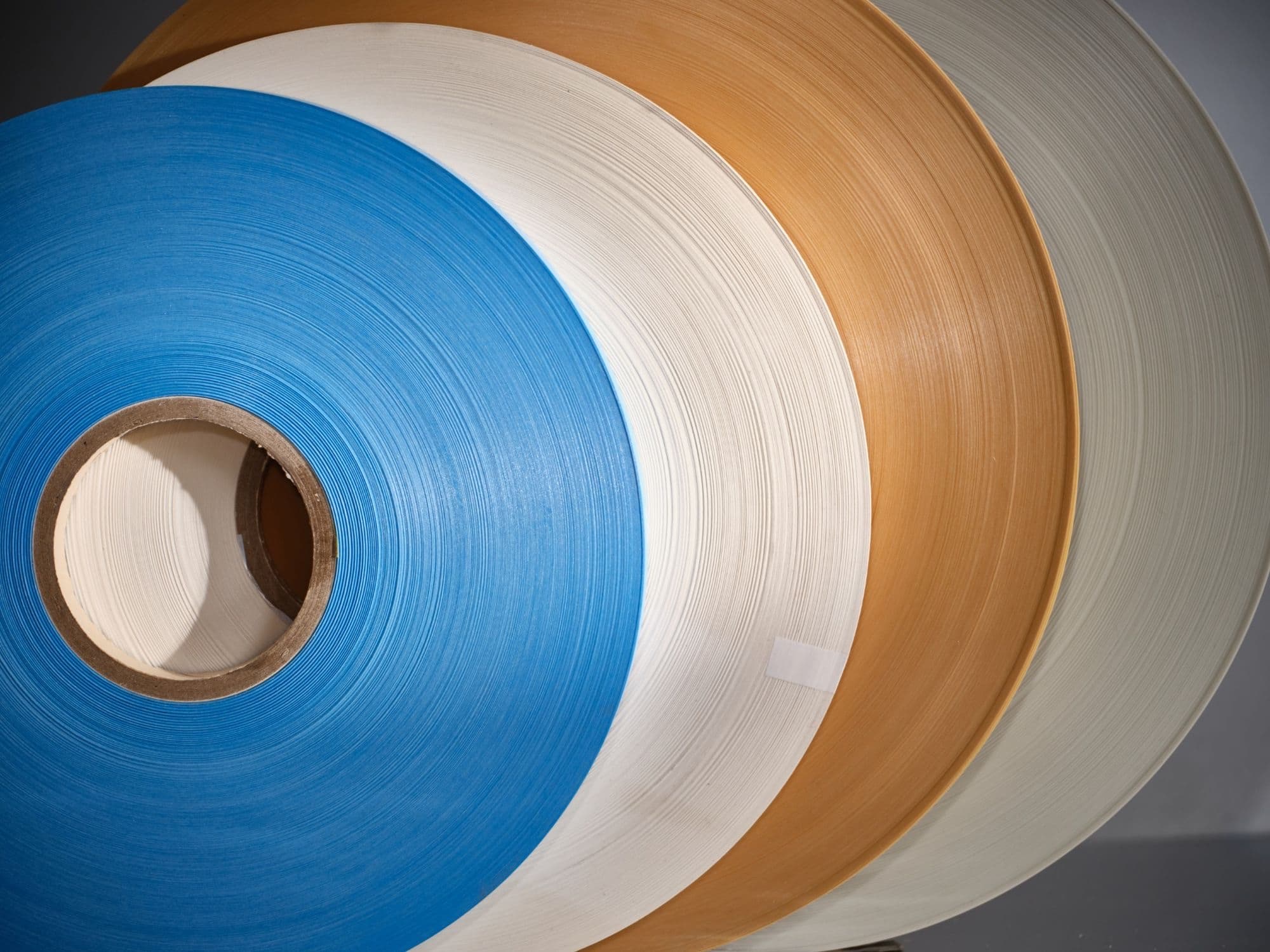 Several rolls of insulation material in blue, white and brown on cores, close-up